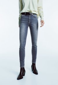 Skinny jeans in mid-blue denim, met een hoge taille, subtiele vervaging en een vijf-pocket ontwerp. Gecombineerd met een lichte trui en hakken.
