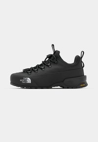 Black hiking shoe with a textured upper, Vibram sole, reinforced toe, laces, and pull tabs for easy wear. Branding on side in white.
