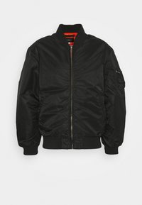 Black bomber jacket with a smooth texture, zip front, ribbed cuffs and hem, and a pocket on the left sleeve with a silver zipper.