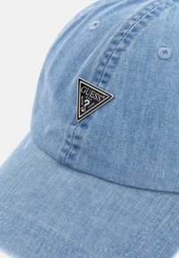 Light blue denim baseball cap featuring a triangular black logo patch, detailed stitching, and a curved brim.