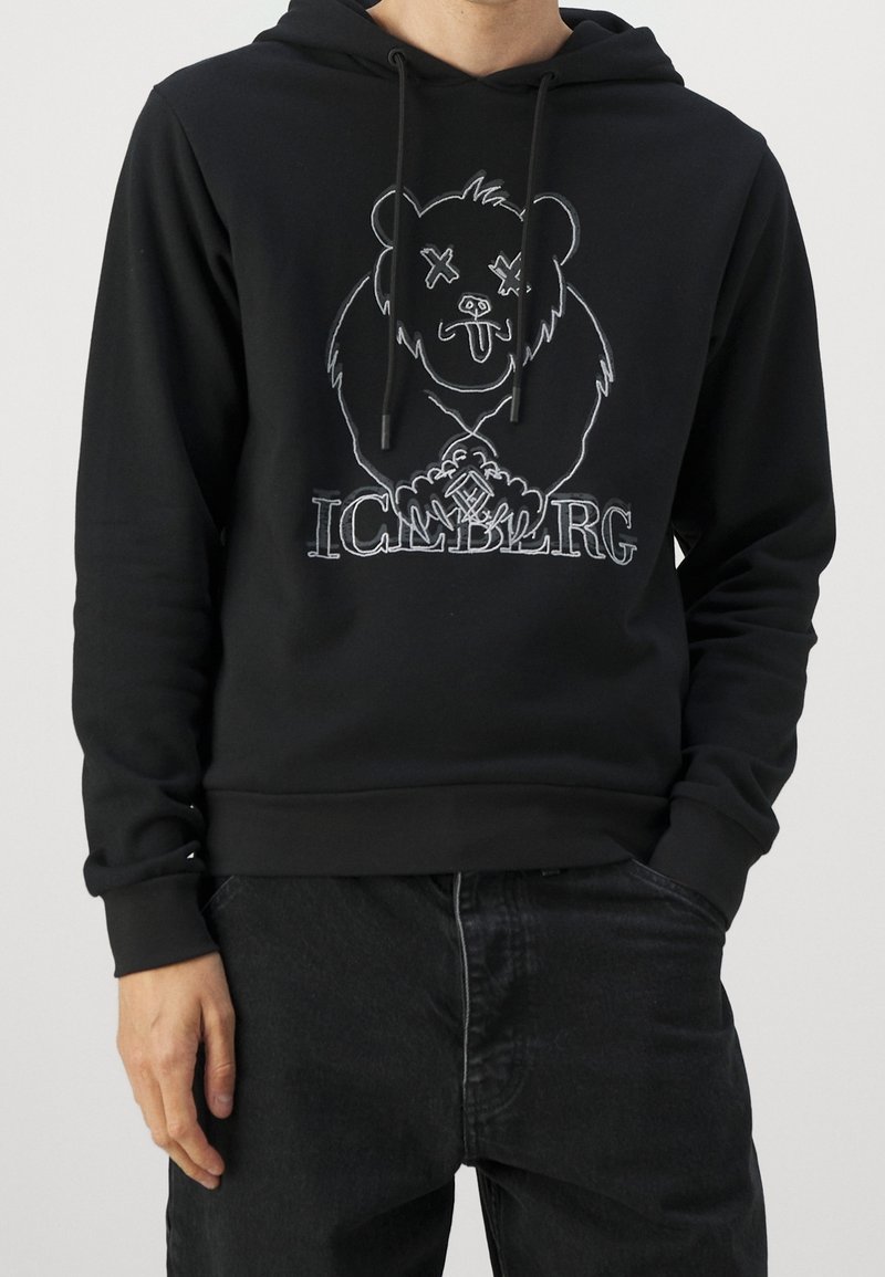 Sweat à capuche noir avec un motif de panda aux yeux en forme de X. Des cordons de serrage et des poignets côtelés complètent le design à coupe décontractée.