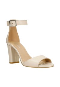 Beige sandalen met hoge hak, enkelriem en gesp, open teen en blokhak, weergegeven tegen een witte achtergrond.