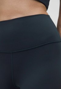 Fekete, magas derekú leggings, rugalmas, matt anyagból, sima textúrával és lapos varratokkal a kényelem érdekében.