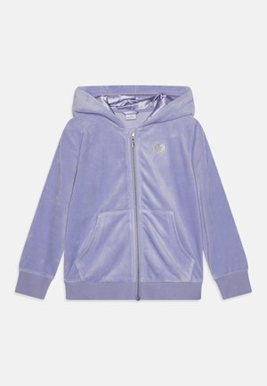 Hoodie zippé en velours violet avec une texture douce, poches avant et un petit détail en forme de cœur argenté sur la poitrine. Poignets et ourlet côtelés.