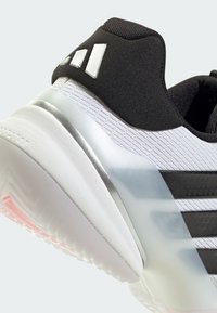 Μαύρο και άσπρο αθλητικό παπούτσι με υφή στο πάνω μέρος, ασημί λεπτομέρειες και καουτσούκ σόλα με ζιγκ-ζαγκ μοτίβο και ροζ στοιχεία.