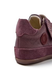 Sneaker bordeaux con texture in suede e pelle, dotato di un logo rotondo, dettagli cuciti e suola piatta in gomma.