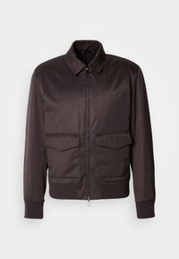 Veste bomber légère marron avec fermeture éclair à l'avant, col pointu et deux poches avant. Poignets et ourlet côtelés, texture lisse sur l'ensemble.