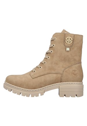 Bottine beige en daim à lacets avec semelle épaisse crantée et petit talon carré, ornée de logos ronds sur le côté et près du haut.