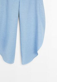Light blue fabric with a rounded hem and a visible side pocket on a plain white background.