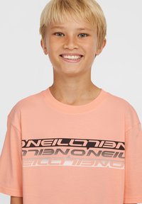 Lichtroze katoenen T-shirt met een gedurfde grafische uitstraling, voorzien van opgestapelde 'O'Neill'-logo's in zwart, grijs en zilver op de borst.