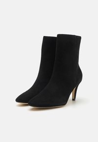 Bottines en daim noir à bout pointu et talon haut fin. Le design présente une silhouette élégante sans éléments métalliques ou accents visibles.
