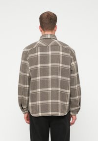 Bruin en beige geruite overhemd gemaakt van textuurstof; heeft een kraag, lange mouwen en knoopmanchetten, met een relaxte pasvorm.