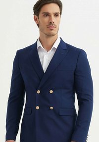 Blazer bleu marine croisé avec des boutons dorés, un col cranté et deux poches avant. Tissu lisse avec une coupe ajustée.