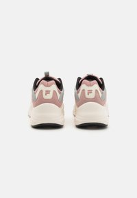 Baskets de sport roses et grises avec une tige texturée, une semelle intermédiaire blanche et une semelle extérieure noire. Elles disposent d'une languette à l'arrière et d'un logo au niveau du talon.