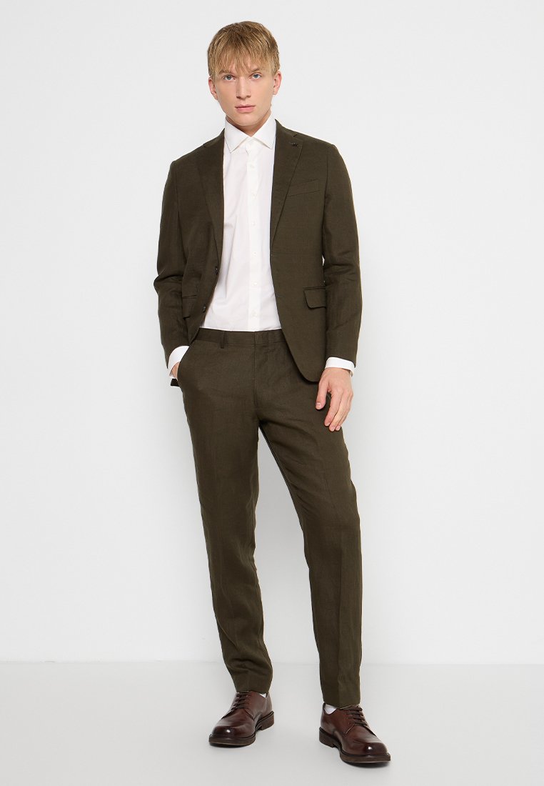 Olivengroene linnen suit met een slim fit, gecombineerd met een wit overhemd. Bruine leren schoenen maken de look compleet. Soepele textuur en op maat gemaakt ontwerp.