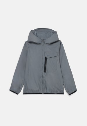 Pilkas užtrauktukas su gobtuvu, su krūtinės kišenių, elastinėmis rankogaliais ir juodomis apdailomis. Pagamintas iš lengvos, vandeniui atsparios medžiagos.