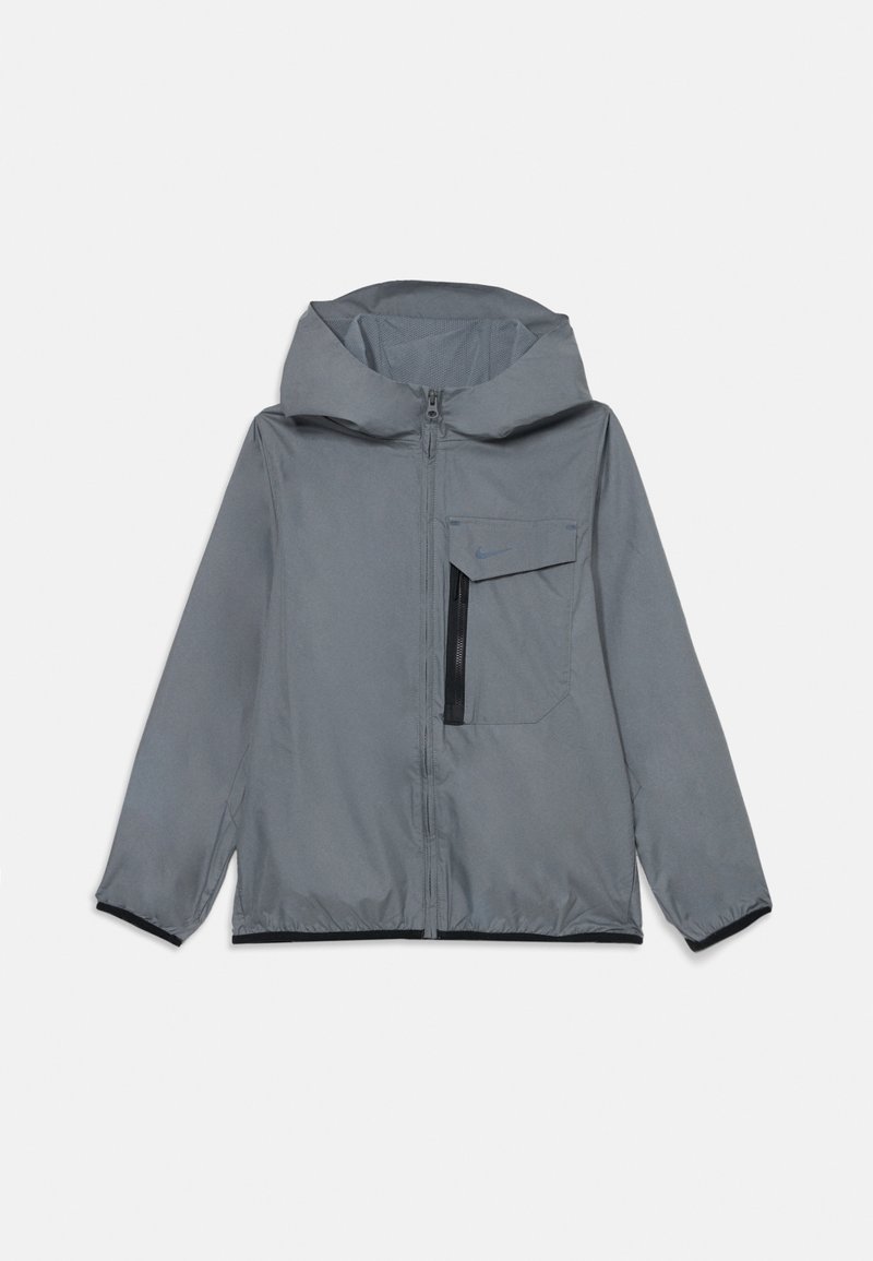 Siva zip-up jakna s kapuco, ki ima žep na prsih, elastične manšete in črne poudarke na robovih. Narejena iz lahkega, vodoodpornega materiala.