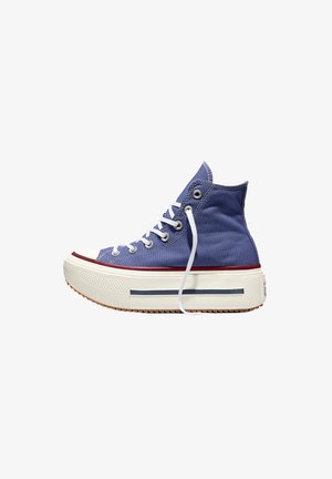 Blauer High-Top-Canvas-Sneaker mit weißen Schnürsenkeln, dicker weißer Plateausohle, rotem Besatz und Gummikappe an der Spitze, seitlich gezeigt.