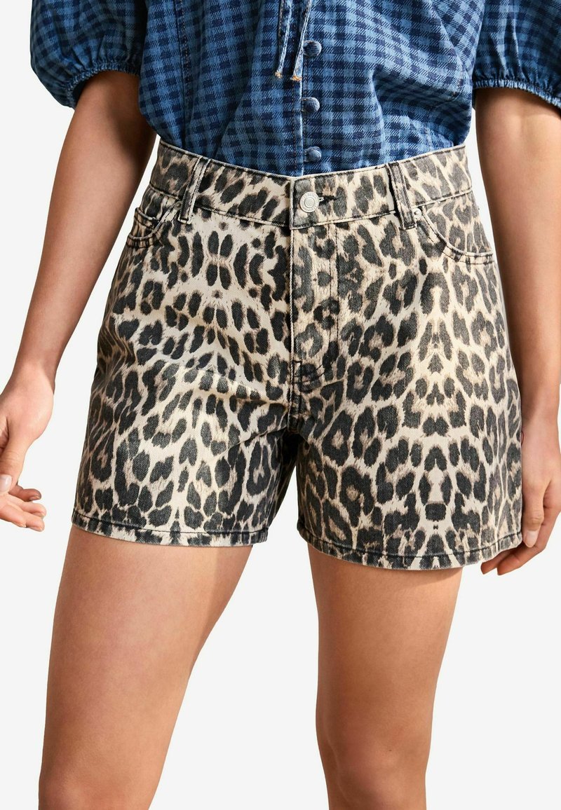 Shorts en denim imprimé léopard avec une taille haute, dotés d'un bouton argenté et d'un design classique à cinq poches. Texture lisse, coupés au-dessus du genou.