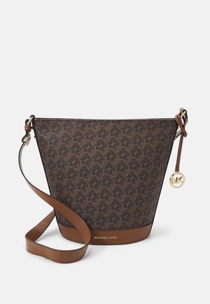 Bruine Michael Kors emmervormige tas met logopatroon, verstelbare schouderriem en ronde gouden MK-bedel op een gestructureerd oppervlak.