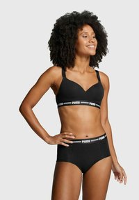 Black athletic bra with a v-neck design and wide straps, paired with high-waisted black underwear featuring a white logo waistband.