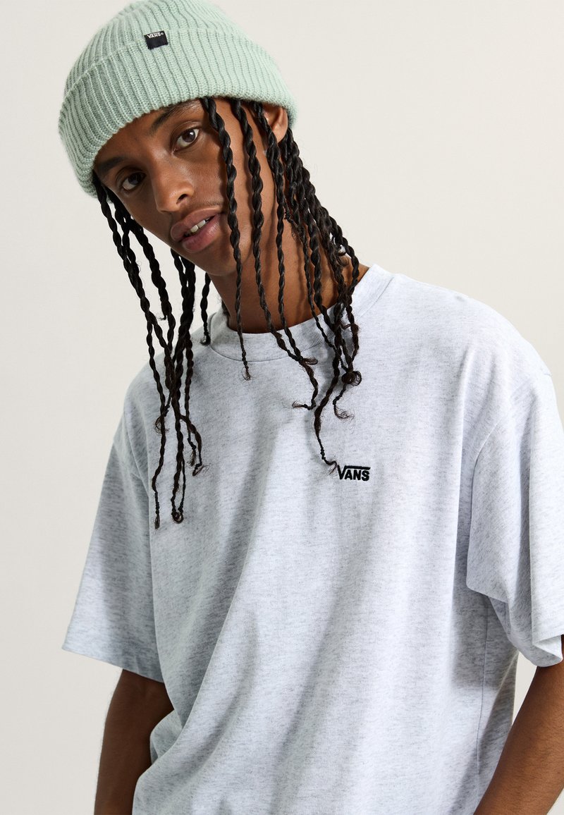 Světle šedé, nadměrné tričko s krátkým rukávem, na kterém se nachází černé logo "VANS". Doplněné mentolově zelenou pletenou čepicí.