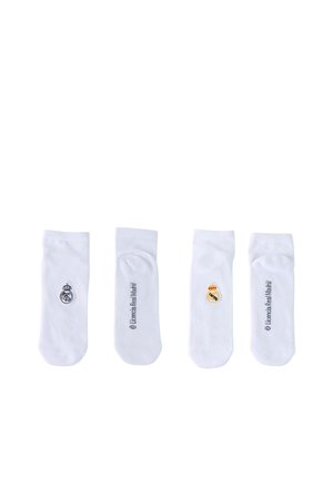 Cztery białe skarpetki do kostek rozłożone na płasko, dwie z czarnym napisem "Licencia Real Madrid" oraz dwie z logo Real Madryt w czerni i kolorze.