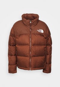 Doudoune marron avec col montant, fermeture éclair à l'avant, poches latérales, et logo blanc The North Face sur la partie supérieure gauche de la poitrine.