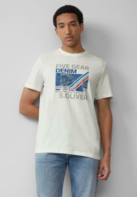 Biała bawełniana koszulka z graficznym nadrukiem z napisem "FIVE GEAR DENIM" w szarych i niebieskich akcentach. Połączona z jasnoniebieskimi dżinsami.
