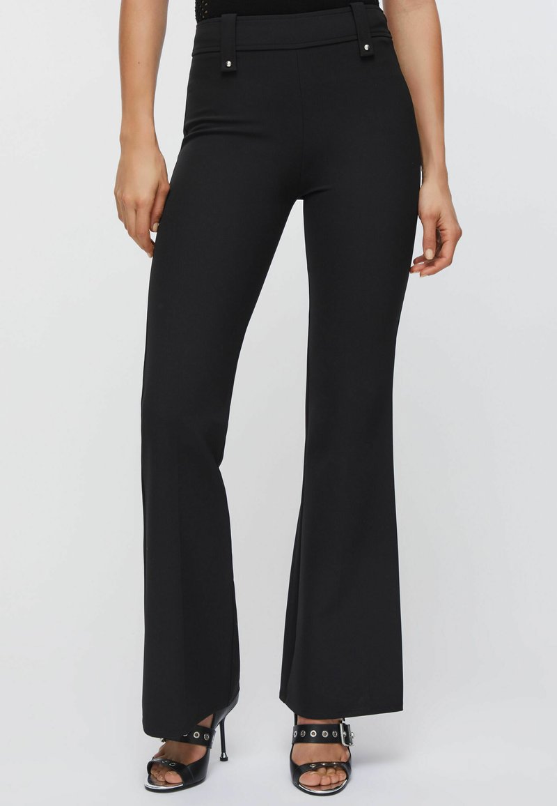 Pantalon noir évasé avec une texture lisse, doté d'une taille haute et d'accents de quincaillerie décorative à la taille.