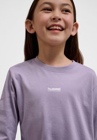 Lila Langarm-T-Shirt aus weichem Stoff, mit Rundhalsausschnitt und dem weißen "hummel PERFORMANCE" Logo im Brustbereich.
