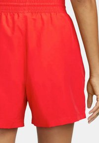 Röda sportshorts med smockad midja, lätt material och avslappnad passform, med rena sömmar och rak fåll.