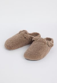 Brown fuzzy slip-on slippers with textured exterior and strap detail, shown on a plain white background.