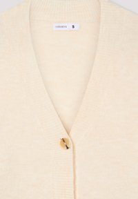 Kremowy kardigan z dekoltem w serek, prążkowanym kołnierzem i pojedynczym okrągłym zapięciem na guzik. Wykonany z miękkiego materiału o lekko teksturowanym wykończeniu.