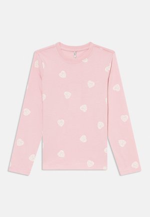 Lyserosa langermet skjorte med hvite hjerte-mønstre som inneholder ordet "GIRL" gjentatt over stoffet.