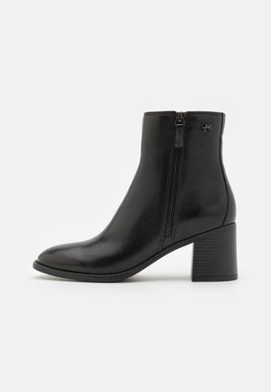 Black leather ankle boot with a side zipper, rounded toe, and a block heel. Features minimal hardware and smooth texture.