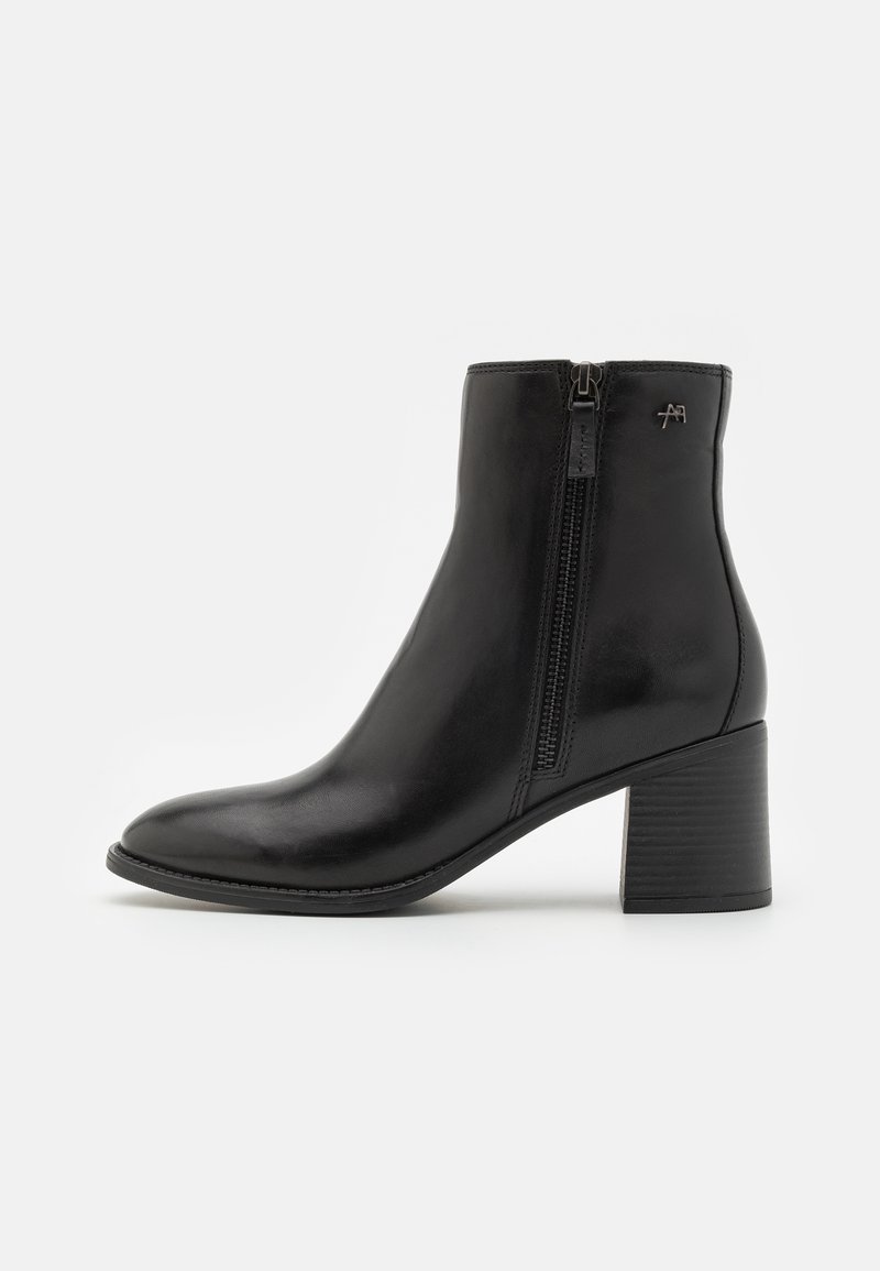 Botín negro de cuero hasta el tobillo con cremallera lateral, punta redonda y tacón cuadrado. Presenta un hardware minimalista y una textura suave.