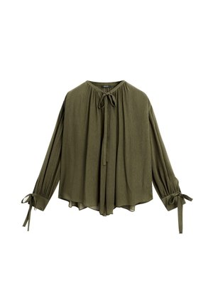 Blouse vert olive avec des manches longues, col à cordon et poignets noués. Texture douce, coupe ample, design fluide et détails de couture minimaux.