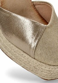 Zapato deslizante de metal dorado con parte superior texturizada y plataforma de yute trenzado. Superficie suave y reflectante con un diseño de punta redondeada.