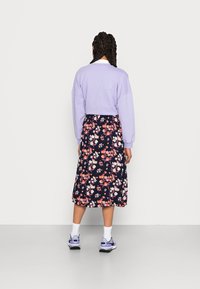 Sweatshirt pullover lavanda acima de uma saia midi floral azul-marinho, com flores em tons de rosa e branco. Combinado com ténis lilás e meias brancas.