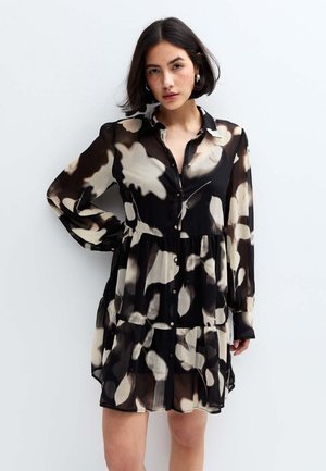 Robe chemise à motifs noir et beige, en tissu léger, fermeture boutonnée à l'avant, manches longues, jupe plissée avec un design en couches.