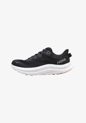 Zapatilla de running negra con parte superior de malla transpirable, media suela blanca acolchada con manchas negras y suela de goma con agarre texturizado.
