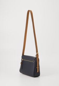 Borsa a tracolla in pelle blu navy con tracolla regolabile marrone, dotata di una tasca frontale con zip e dettagli in oro. Texture liscia.