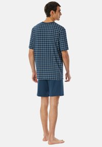 Marineblaues Kurzarmhemd mit Karomuster, kombiniert mit passenden Shorts. Weiches Material, lockere Passform und schlichtes Design.
