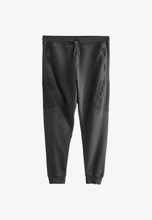 Tmavosivé tepláky z mäkkej látky s zužujúcimi sa nohavicami, elastickým pásom a viacerými vreckami so zipsom po bokoch.