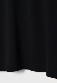 Crni materijal s vidljivim šavovima duž ruba, koji prikazuje blage nabore i teksturu.