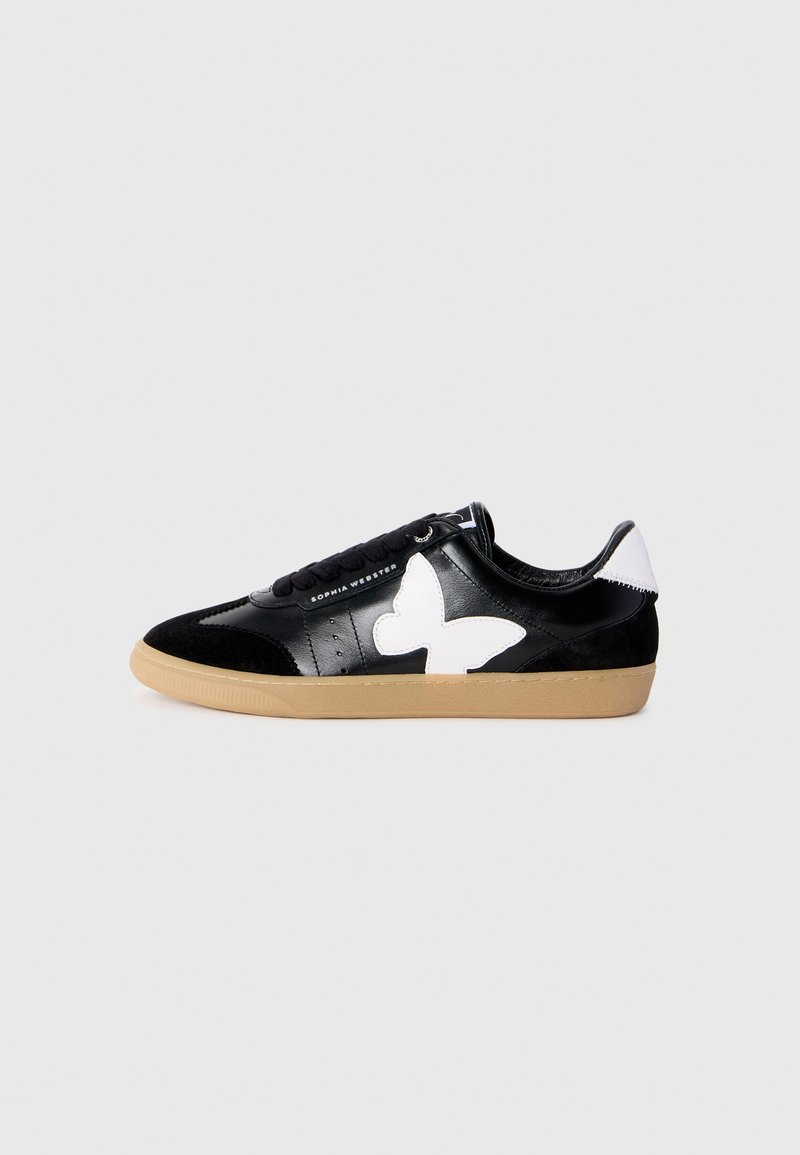 Sneaker nera bassa con suola in gomma, dettaglio bianco a forma di farfalla sul lato e sul tallone, e lacci neri, esposta su uno sfondo semplice.