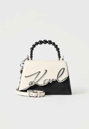 Petit sac à main noir et blanc avec poignée en perles noires, bandoulière amovible et décoration argentée "Karl" sur le rabat avant.