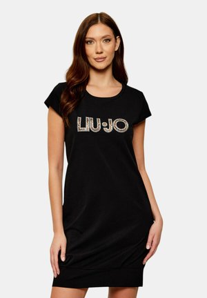 Donna con capelli castani lunghi che indossa un vestito nero a maniche corte con il logo "LIU·JO" stampato a motivo leopardato sul petto.