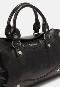 Sac à main Liu Jo en cuir noir avec deux anses, boutons argentés et surface subtile discrète.